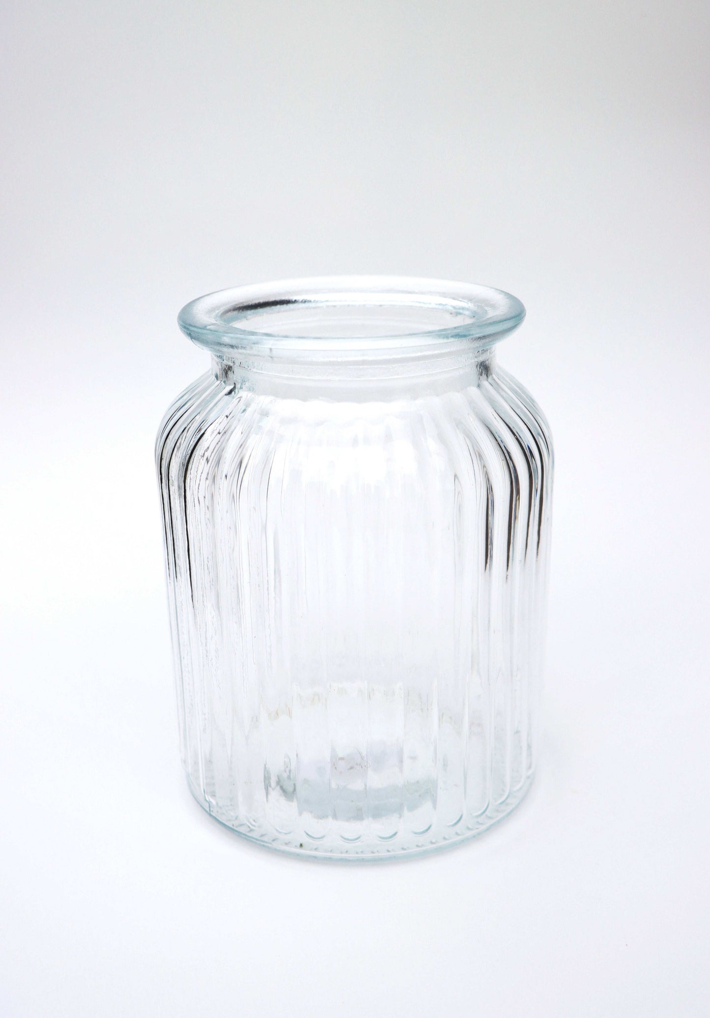 Clear glass jar with ribbed texture on a white background.