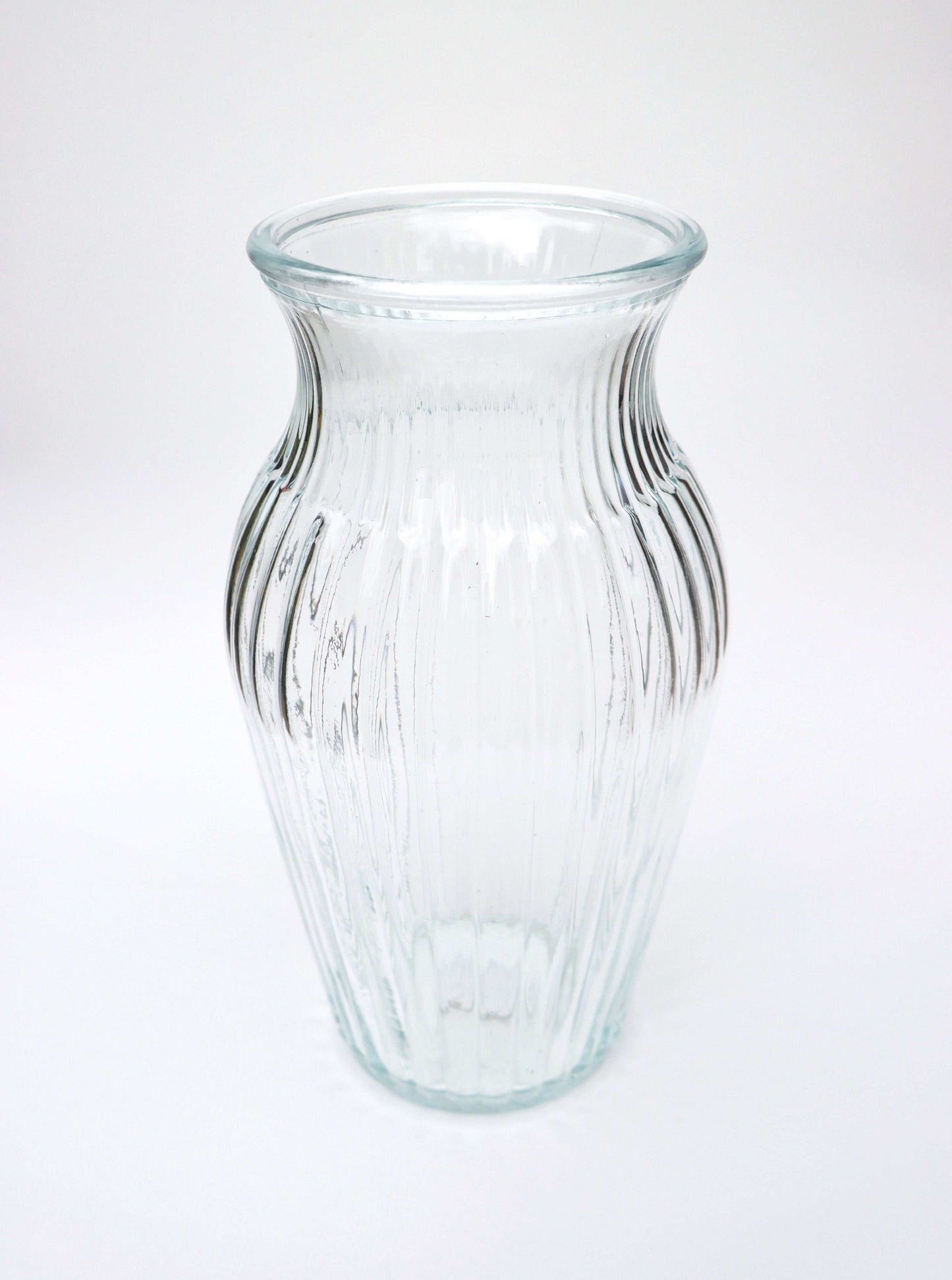 Clear ribbed glass vase with a flared top on a white background.