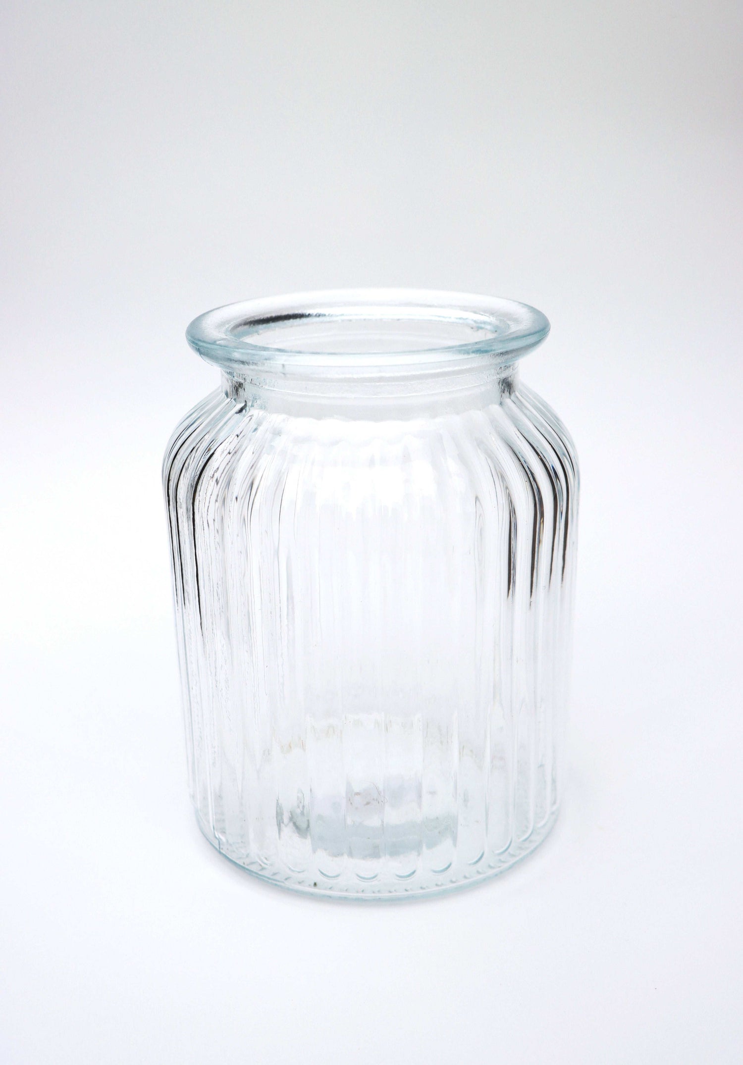 Clear glass jar with ribbed texture on a white background.
