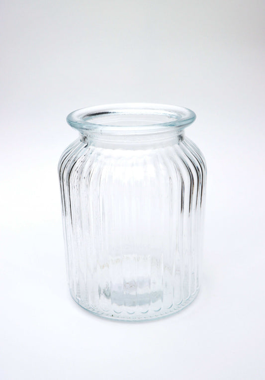 Clear glass jar with ribbed texture on a white background.